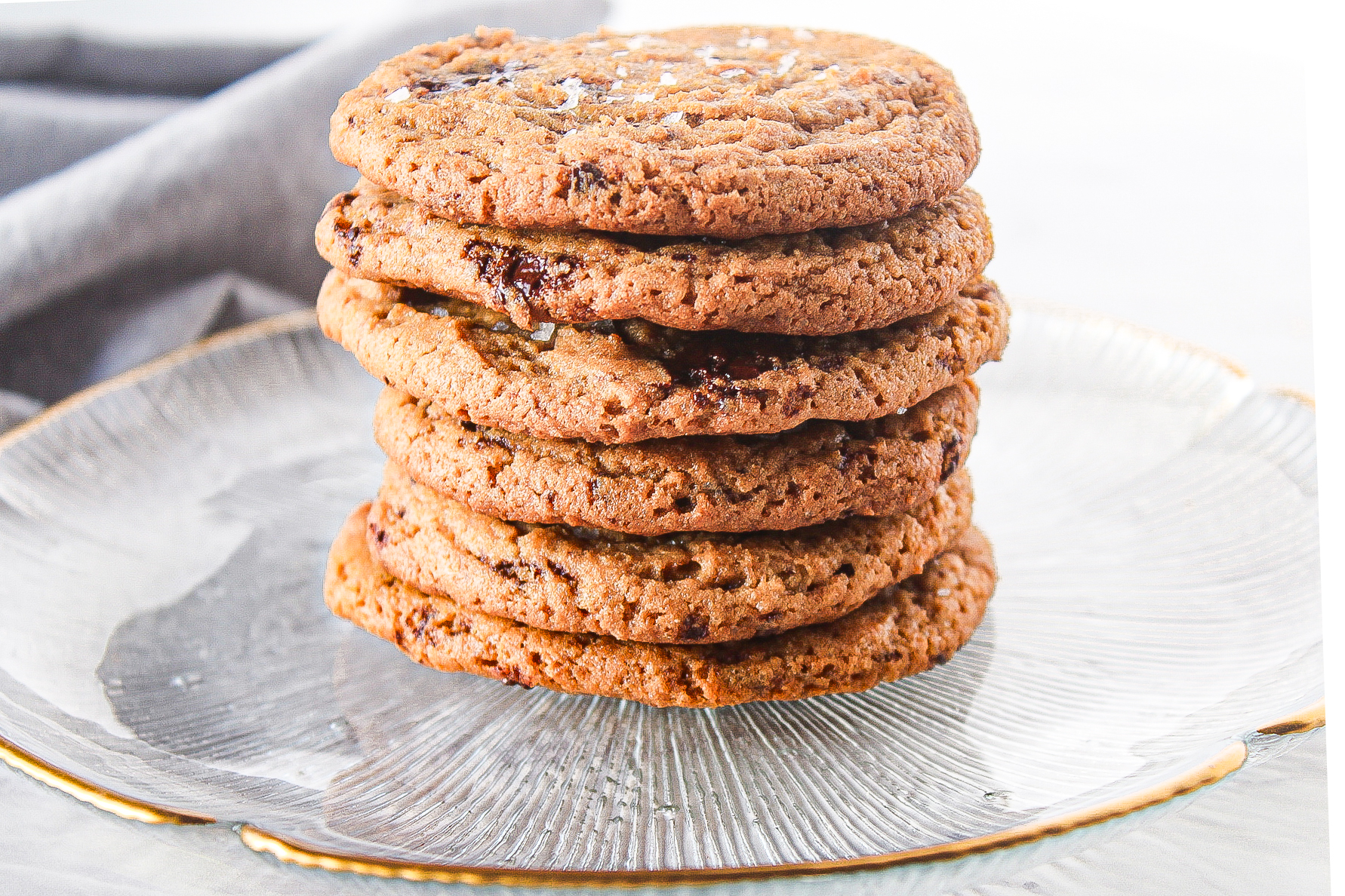 einkorn chocolate chip cookies stacked high on top of a clear glass plate