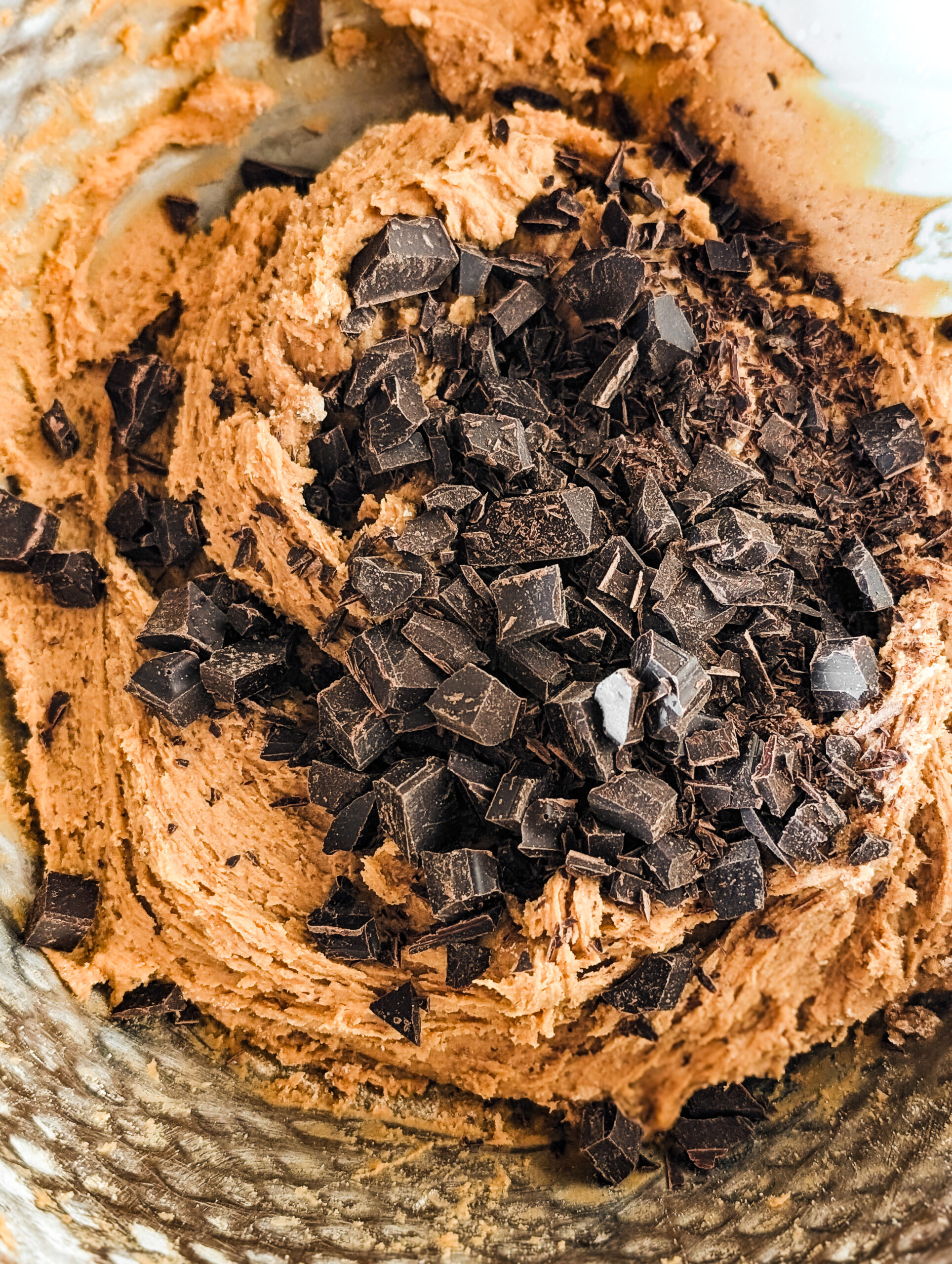 bowl with chopped baking chocolate on top of cookie dough