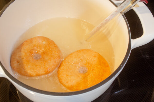 frying the backside of two donuts in coconut oil