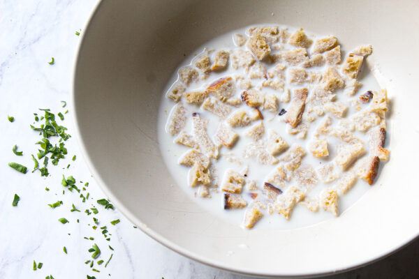 cubed bread soaking in milk inside of a ceramic bowl