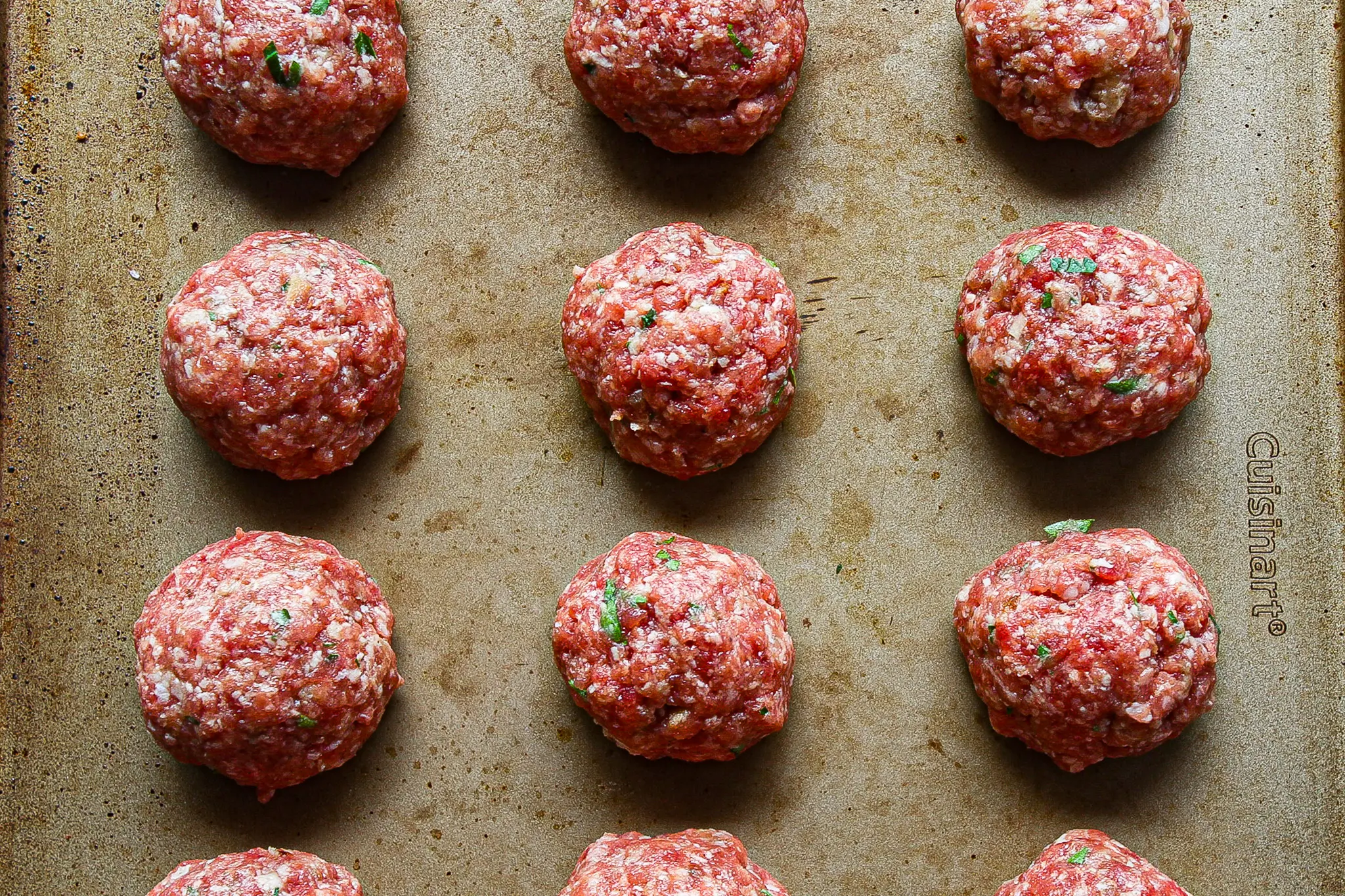 close-up of uncooked italian meatballs on a baking sheet ready to be frozen for storage