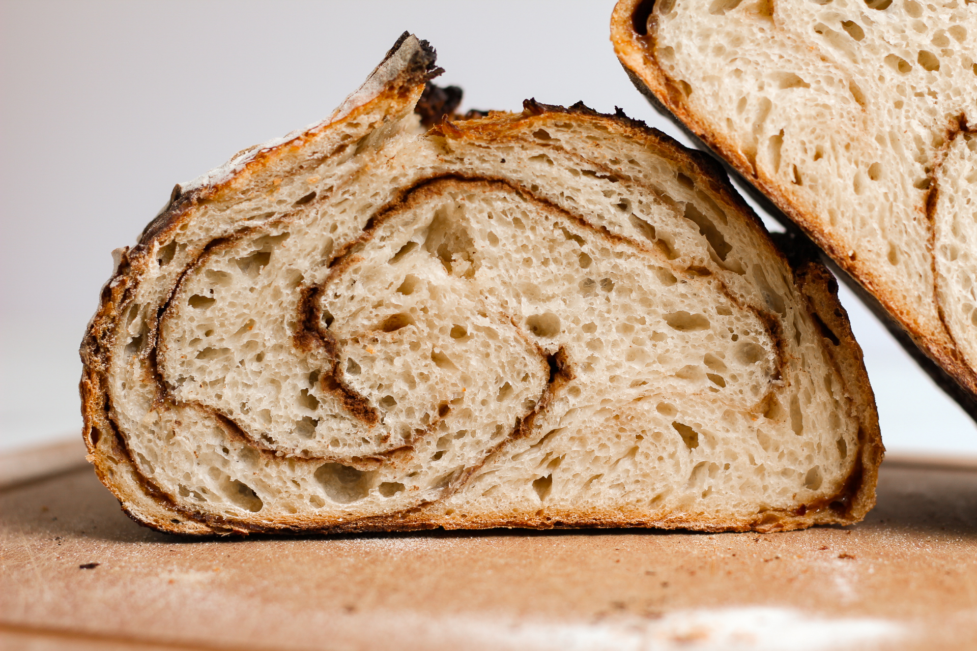 sourdough loaf cut in half with the other half resting on top with a display of a cinnamon swirl inside