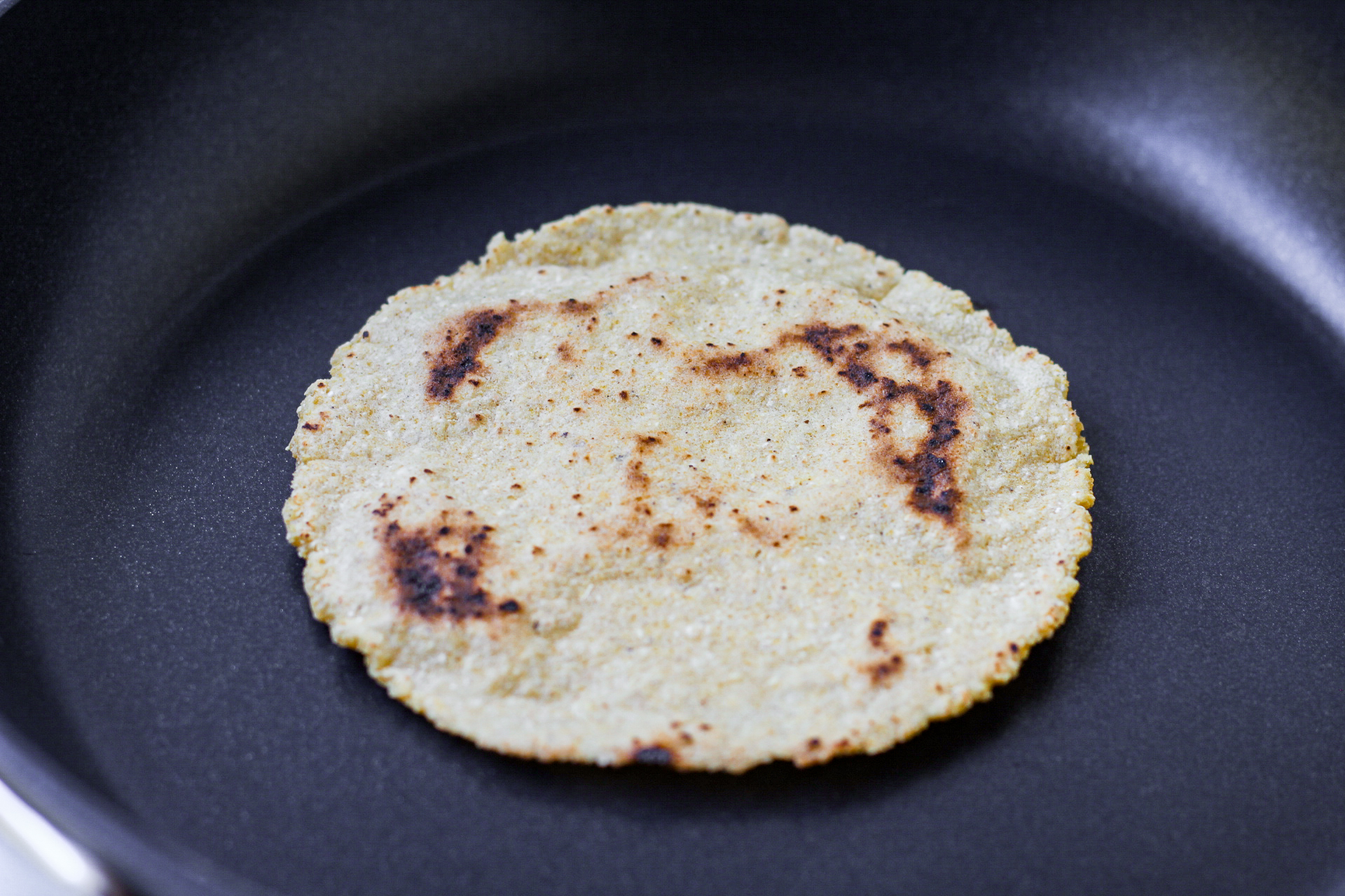 charred corn tortilla in skillet