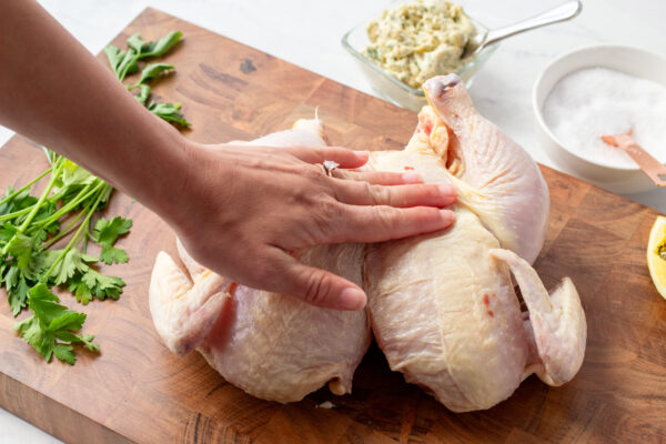 demonstration of breast bones being pressed down on to flatten the chicken for spatchcocking cooking method 