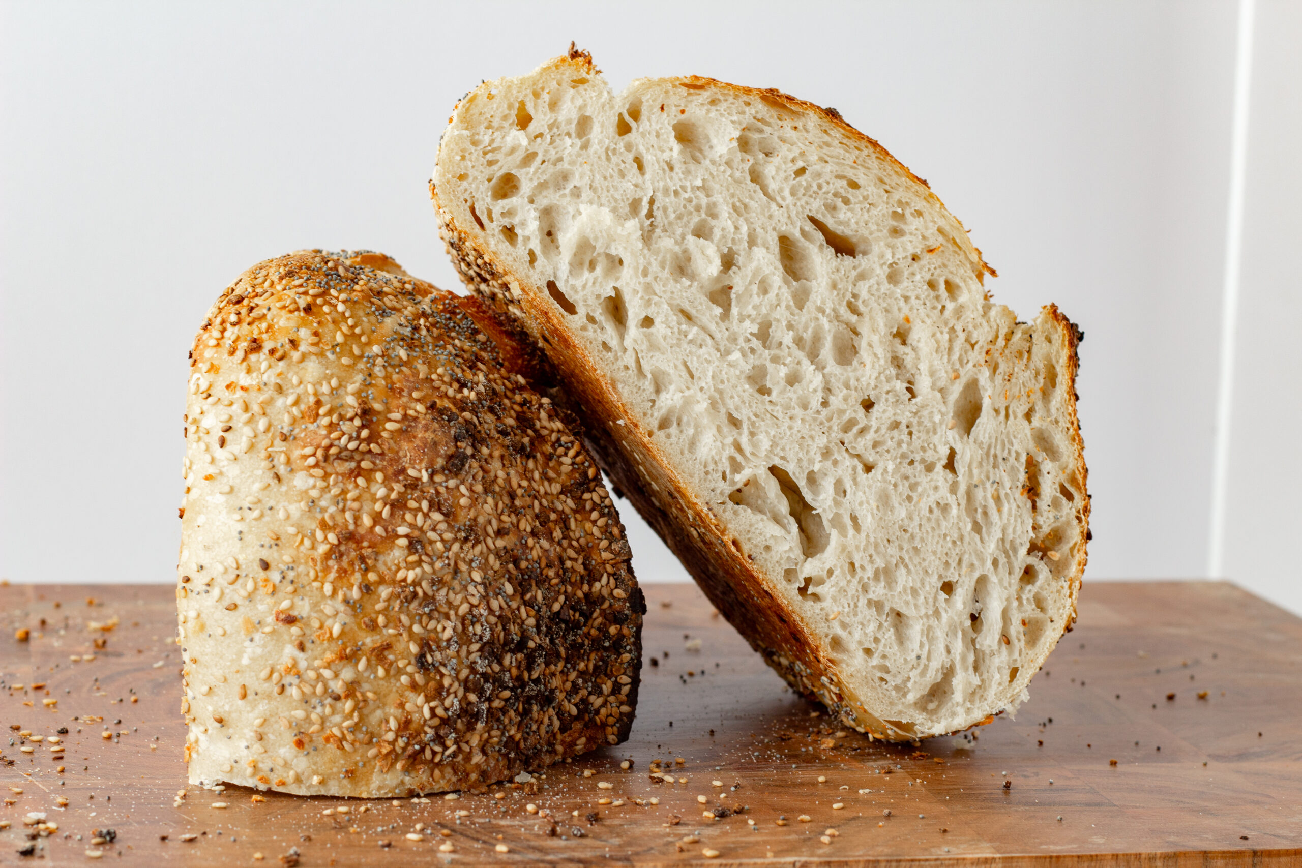 sourdough loaf coated in everything bagel seasoning cut in half with both pieces resting on eachother