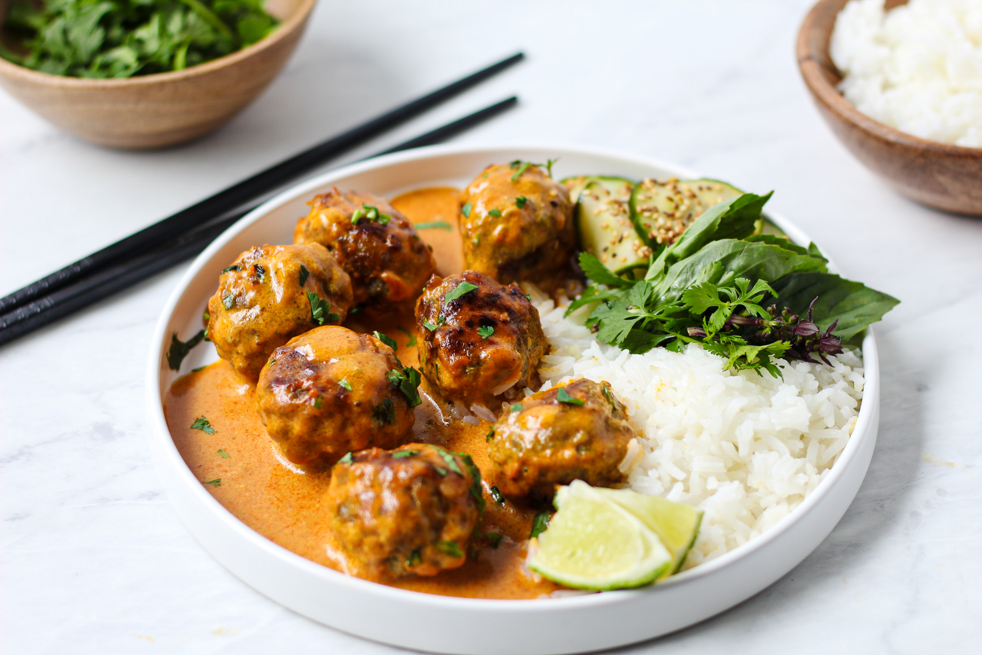 white plate of orange coconut curry sauce and meatballs with rice and jasmine rice