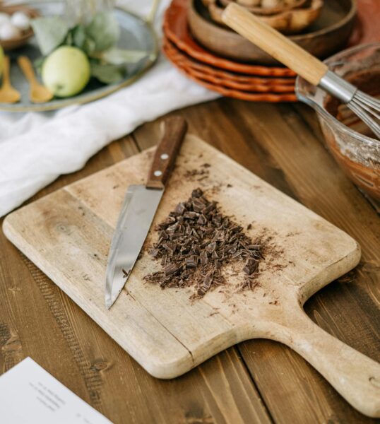 Chopped chocolate on a wooden board in a cozy kitchen setting. Ideal for culinary themes.