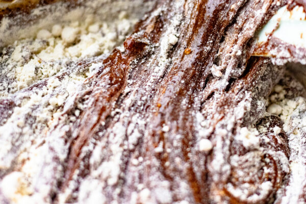 Einkorn all-purpose flour being folded into chocolate brownie batter showing the thirds folding method