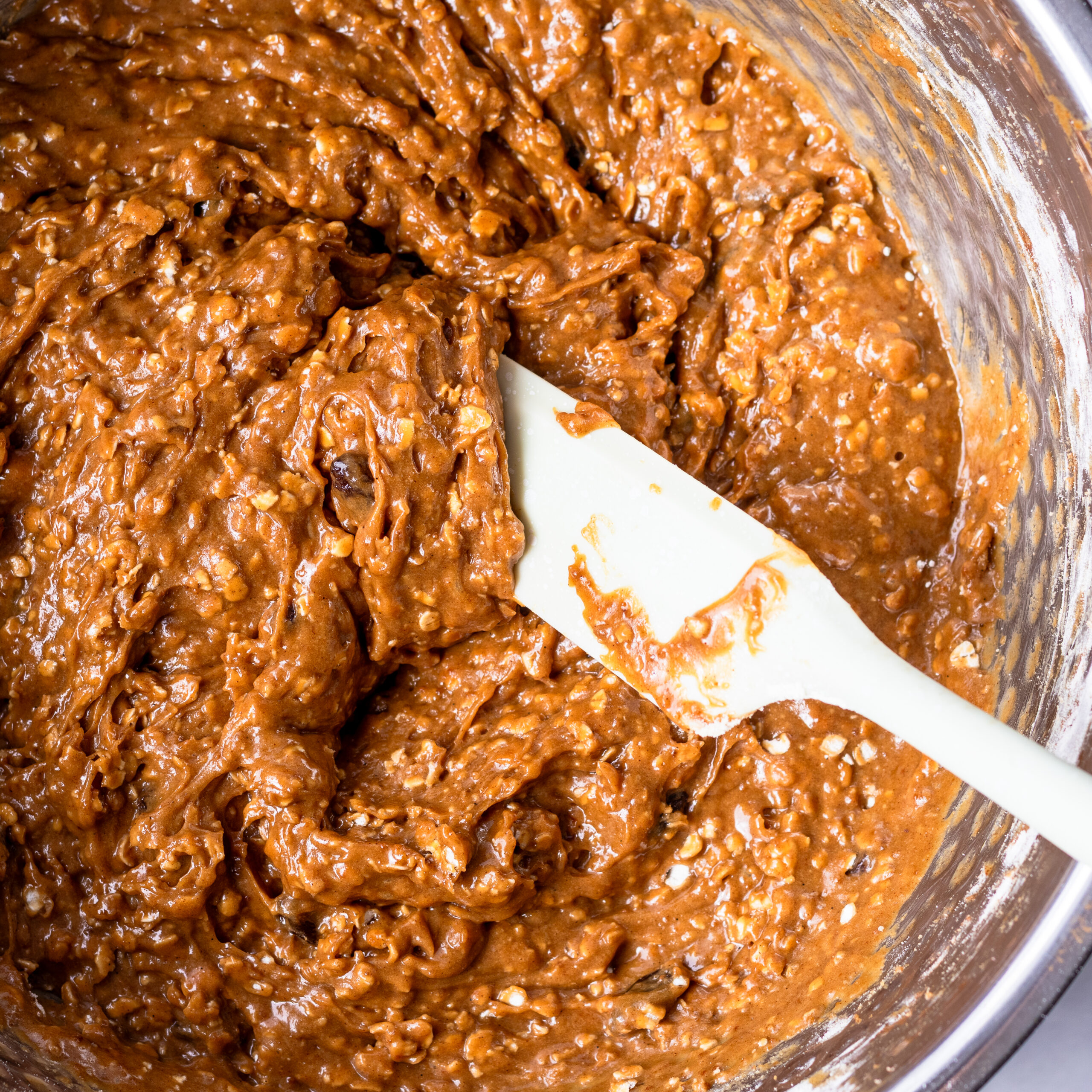 Einkorn oatmeal raisin cookie dough mixed in a stainless steel bowl with a white spatula