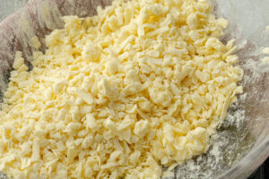 Shredded frozen butter coated in flour in a glass mixing bowl
