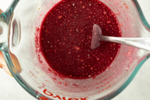 Deep red cherry juice in a glass measuring cup with a spoon