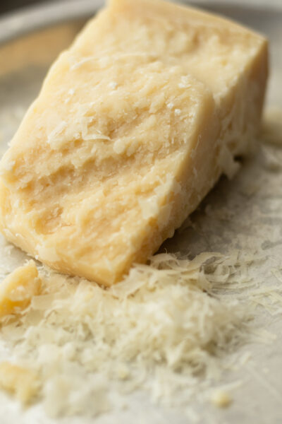 Block of parmigiano reggiano finely grated for creamy pasta sauce