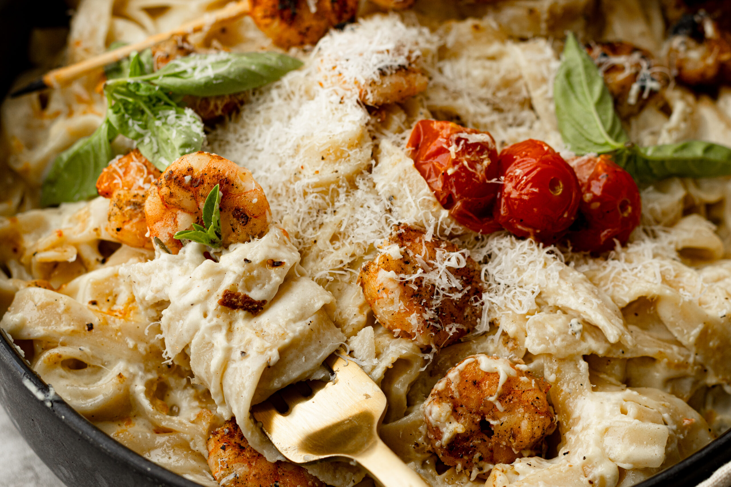 Parmigiano cream pasta with charred grilled shrimp, roasted cherry tomatoes, and fresh basil