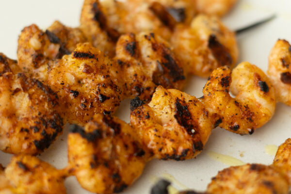 Charred grilled shrimp skewers seasoned with salt and pepper